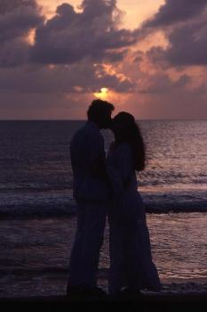 Featured is a photo of a couple enjoying a romantic moment on the beach.  Photographer unknown.